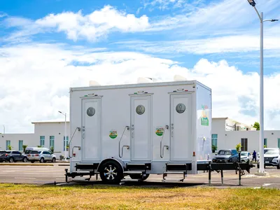 Island Sanitation Plus AC restroom trailer set up in a parking lot for an event