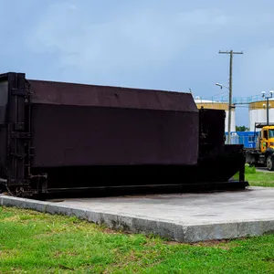 Island Sanitation Plus branded compactor bin on a concrete pad at an industrial site