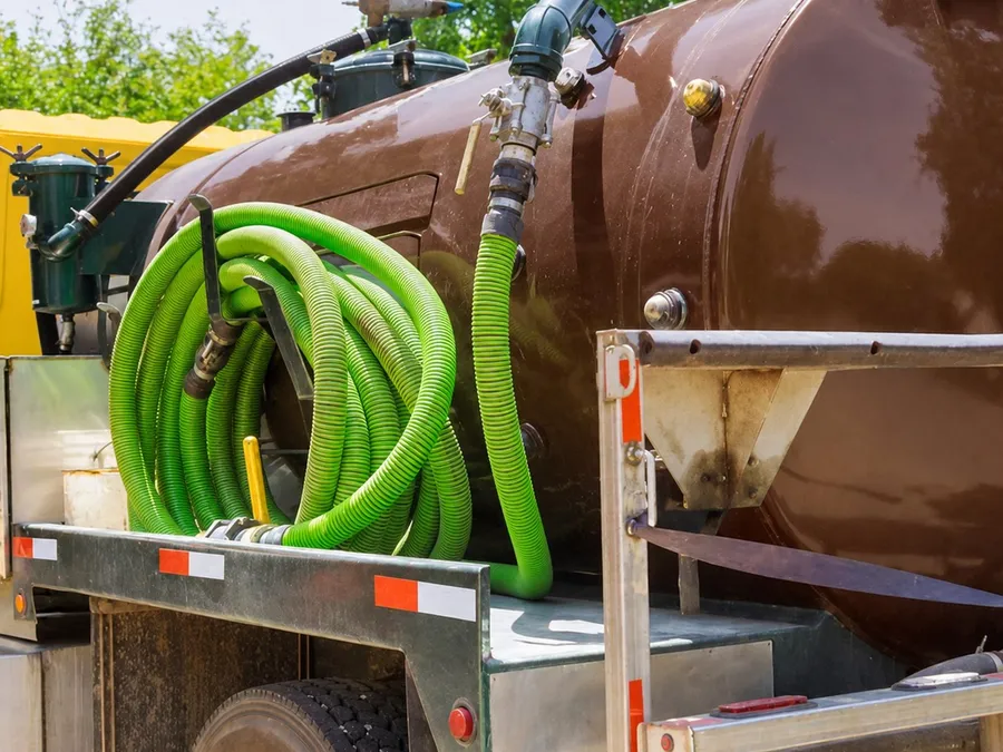 Island Sanitation Plus septic tanker truck with coiled green vacuum hose attached