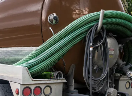Rear view of an Island Sanitation Plus septic tanker truck with vacuum hoses and pump equipment