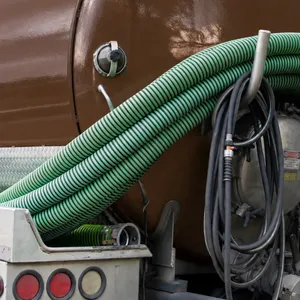 Rear view of an Island Sanitation Plus septic tanker truck with vacuum hoses and pump equipment