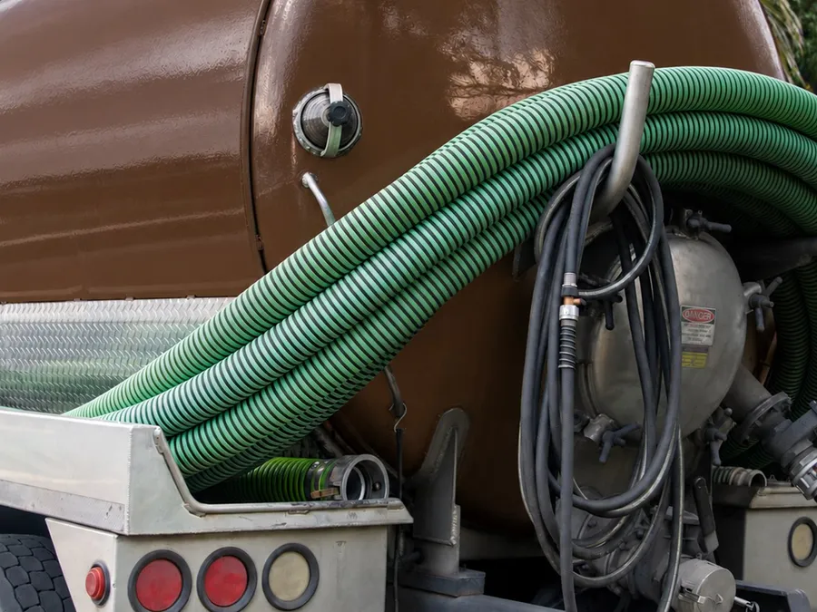 Rear view of an Island Sanitation Plus septic tanker truck with vacuum hoses and pump equipment