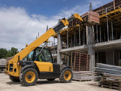 Telescopic forklift lifting building materials to an upper floor on a multi-storey construction site