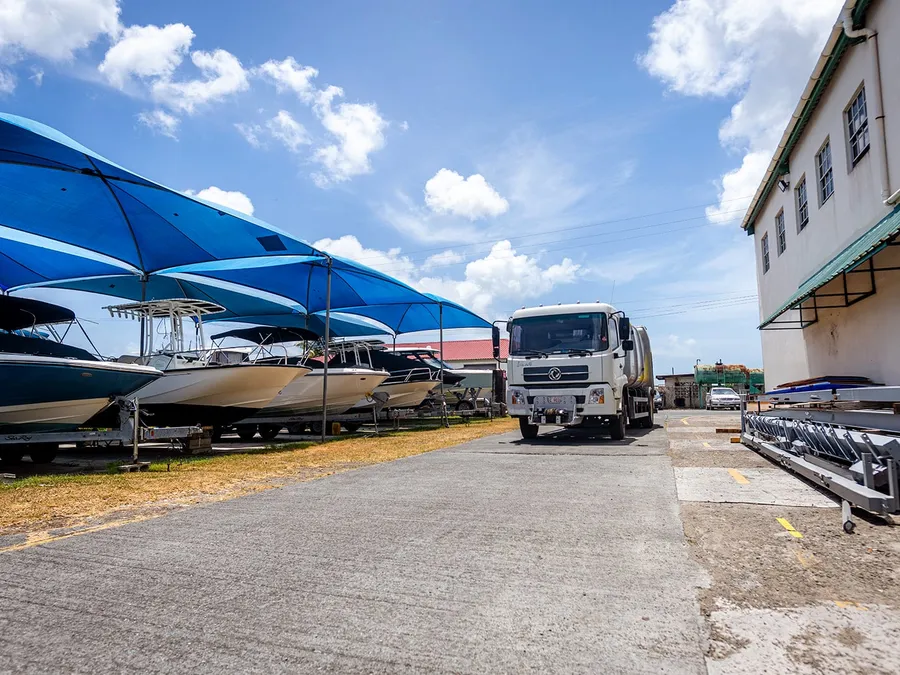 Island Sanitation Plus service truck at a marina in Antigua, boats visible under blue canopies