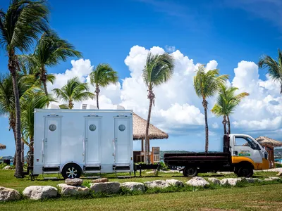 Island Sanitation Plus AC restroom trailer and service truck set up beachfront at a resort in Antigua