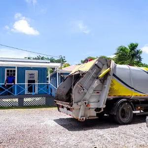 Island Sanitation Plus rear-loader truck with compactor door open, servicing a commercial site